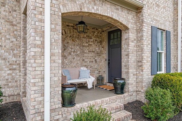 entrance to property featuring brick siding and covered porch