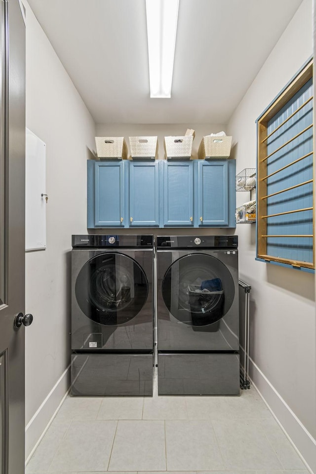 laundry room with cabinet space, light tile patterned flooring, washing machine and dryer, and baseboards