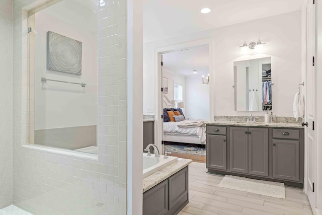 full bathroom featuring vanity, wood tiled floor, a spacious closet, ensuite bathroom, and walk in shower