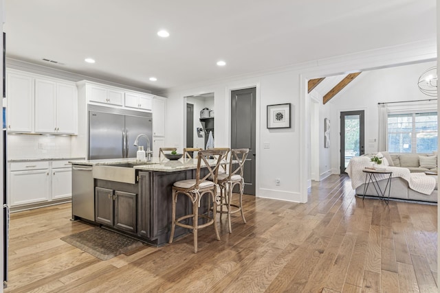 kitchen with tasteful backsplash, stainless steel appliances, light wood-style floors, a breakfast bar area, and white cabinets