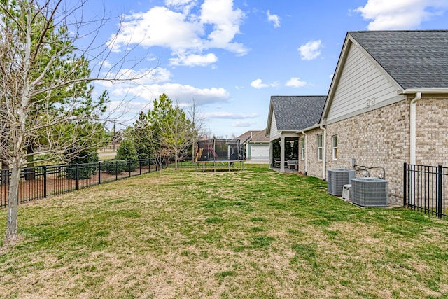 view of yard with a trampoline, a fenced backyard, and central AC