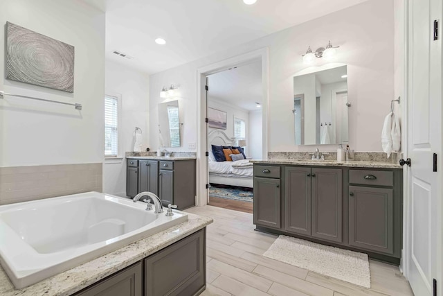 ensuite bathroom featuring ensuite bath, vanity, a garden tub, and wood finished floors