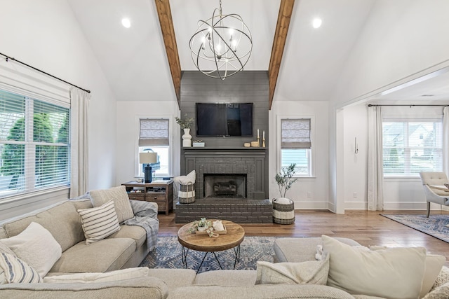 living room with a notable chandelier, a fireplace, high vaulted ceiling, and wood finished floors