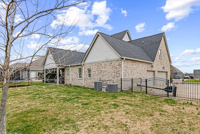 view of side of home featuring a lawn, a trampoline, central AC, fence, and a garage