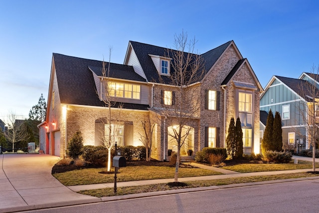 view of front facade with concrete driveway, a garage, brick siding, and roof with shingles