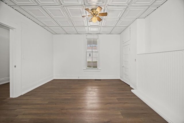 empty room with ceiling fan, baseboards, an ornate ceiling, and dark wood-style floors