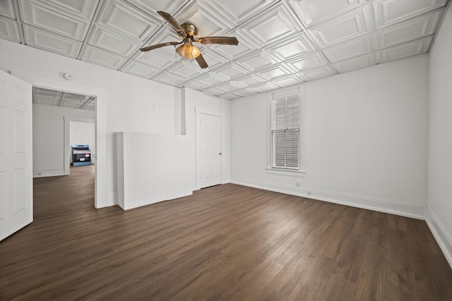 unfurnished room with baseboards, dark wood-style floors, ceiling fan, and an ornate ceiling