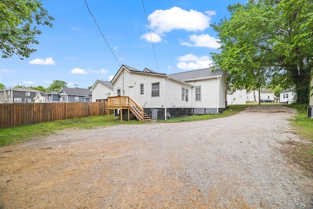 rear view of property with fence, a residential view, and metal roof