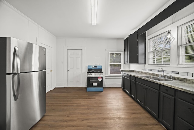 kitchen featuring dark wood-style floors, stainless steel appliances, dark cabinets, a sink, and decorative light fixtures
