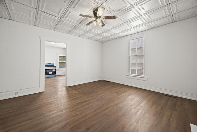 empty room featuring an ornate ceiling, baseboards, ceiling fan, and dark wood finished floors