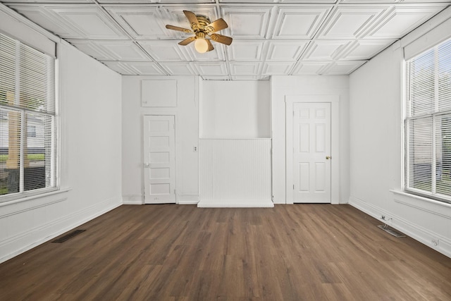 empty room with an ornate ceiling, ceiling fan, visible vents, and dark wood-style flooring