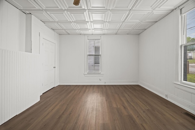 unfurnished room with dark wood-type flooring, an ornate ceiling, visible vents, and baseboards