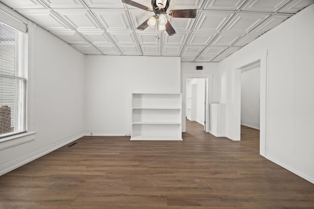 empty room featuring an ornate ceiling, wood finished floors, baseboards, and ceiling fan