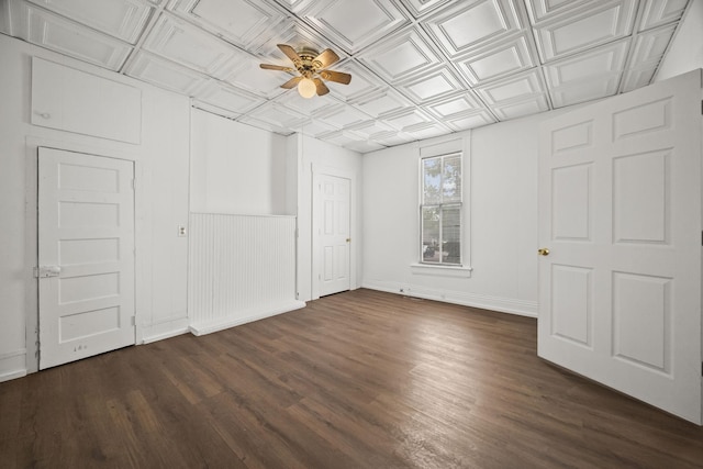 unfurnished bedroom featuring an ornate ceiling, a ceiling fan, baseboards, and dark wood-style flooring