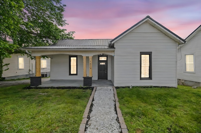 single story home featuring a porch, a yard, and metal roof