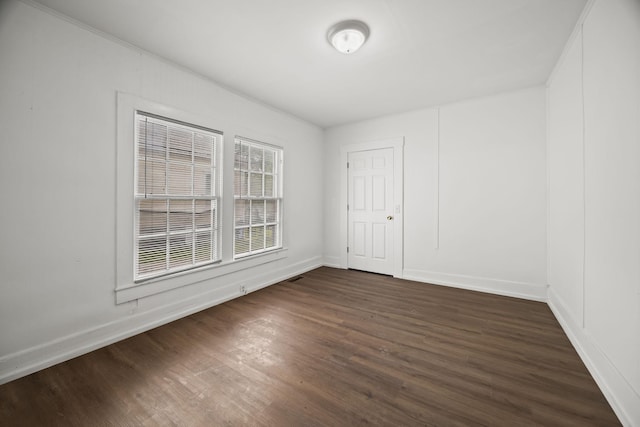 spare room featuring visible vents, baseboards, and dark wood-style floors