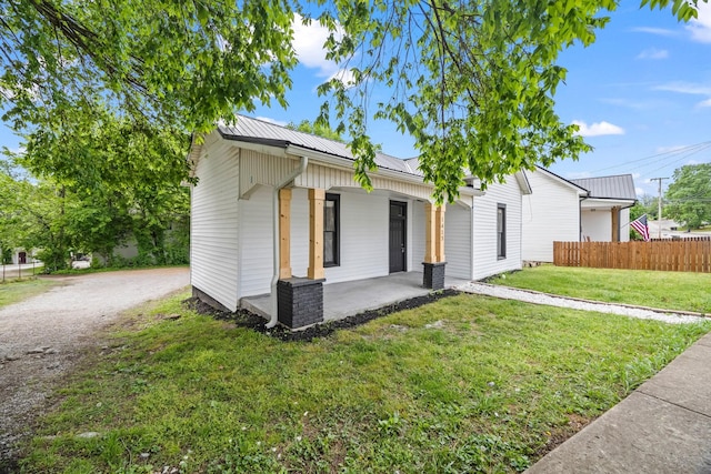 view of front of property with fence, a front lawn, covered porch, and metal roof