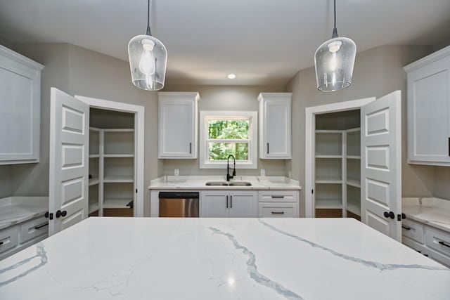 kitchen featuring light stone countertops, white cabinetry, a sink, hanging light fixtures, and stainless steel dishwasher