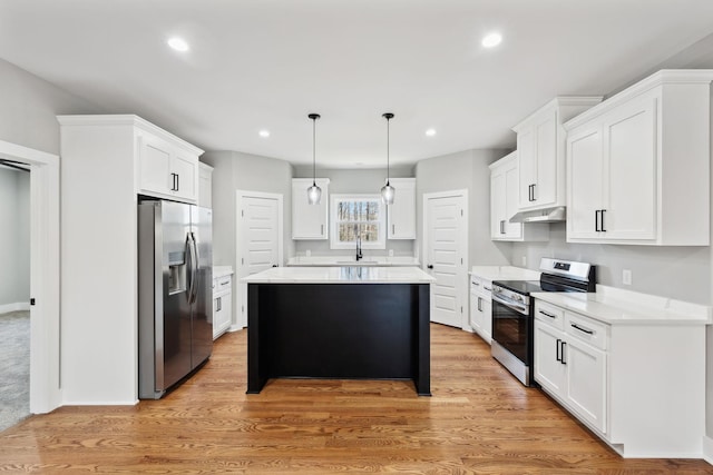 kitchen featuring under cabinet range hood, appliances with stainless steel finishes, a kitchen island, and light countertops