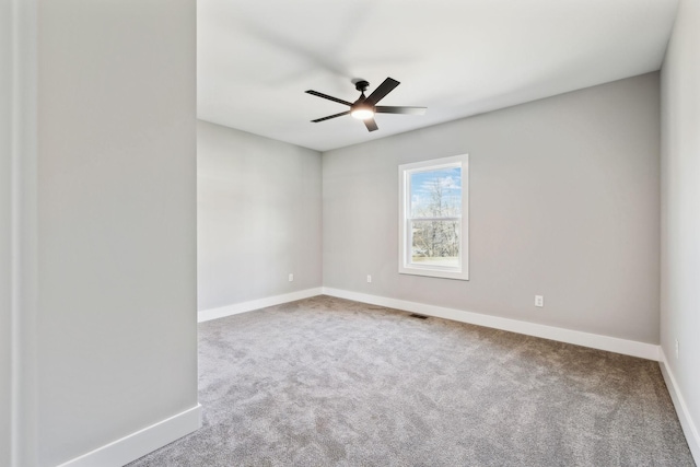 carpeted empty room with visible vents, baseboards, and a ceiling fan