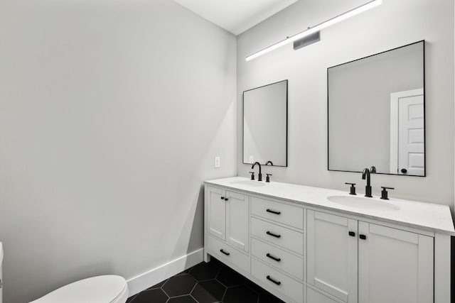 bathroom featuring tile patterned flooring, toilet, baseboards, and a sink