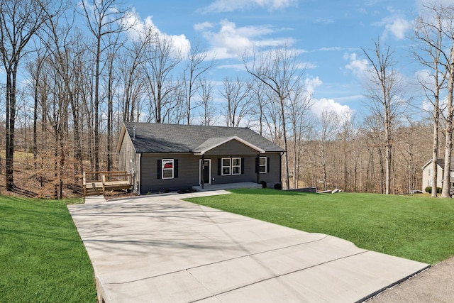 view of front facade with covered porch, concrete driveway, a front lawn, and a wooded view