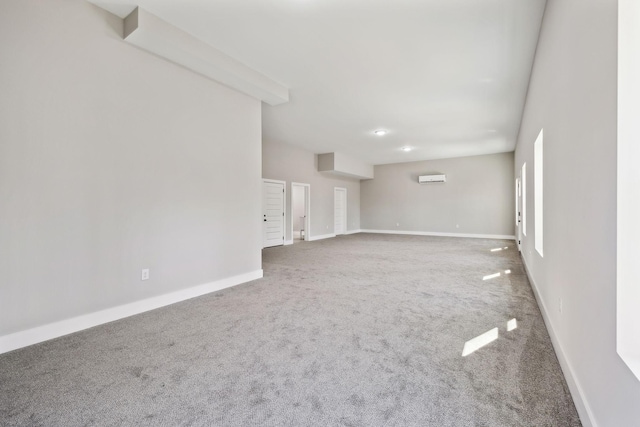 spare room with an AC wall unit, baseboards, and carpet floors