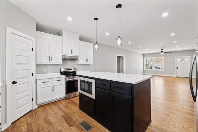 kitchen featuring dark cabinetry, electric range, built in microwave, white cabinets, and under cabinet range hood