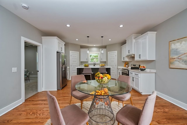 dining area featuring light wood finished floors, recessed lighting, and baseboards