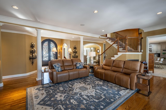 living room featuring a wealth of natural light, stairway, wood finished floors, and ornate columns