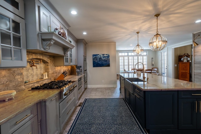 kitchen with a sink, tasteful backsplash, glass insert cabinets, baseboards, and stainless steel gas cooktop