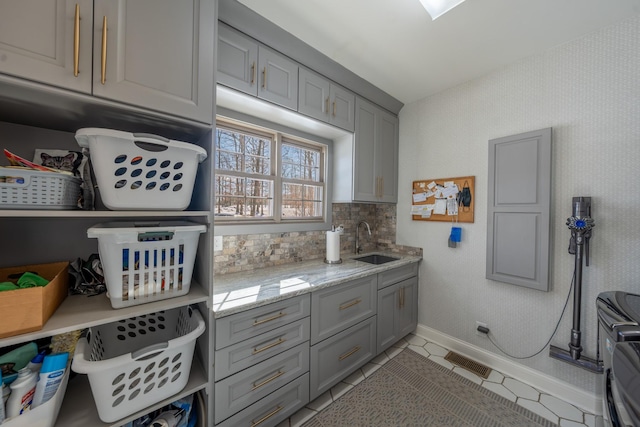 interior space featuring visible vents, gray cabinets, a sink, tasteful backsplash, and light stone countertops