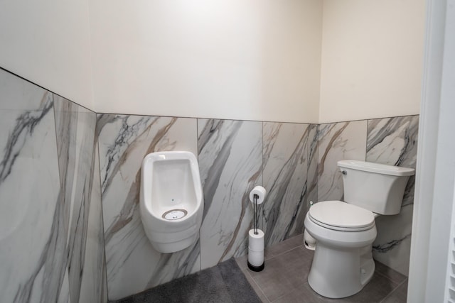 bathroom with tile patterned floors, wainscoting, toilet, and tile walls