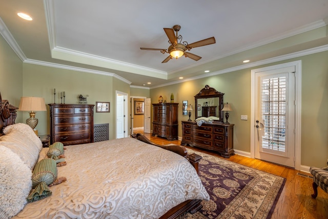 bedroom featuring recessed lighting, crown molding, a raised ceiling, and wood finished floors