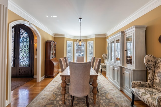 dining room with light wood finished floors, baseboards, ornamental molding, french doors, and arched walkways