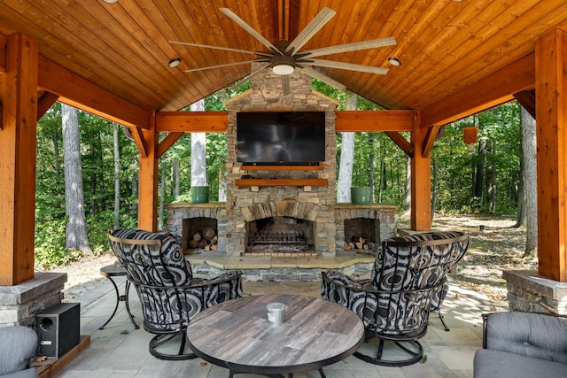 view of patio featuring ceiling fan, a gazebo, and an outdoor stone fireplace