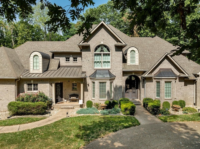 view of front of house featuring metal roof, a patio, brick siding, and a standing seam roof