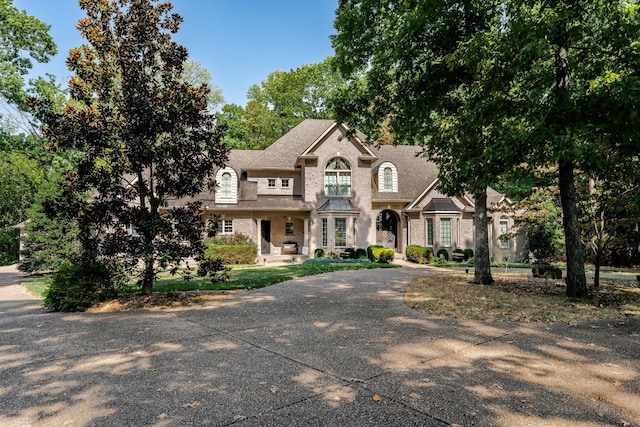 french country inspired facade with concrete driveway, french doors, and brick siding