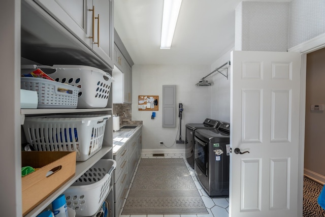 washroom with a sink, baseboards, cabinet space, and washing machine and dryer