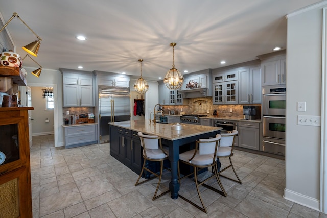 kitchen featuring a breakfast bar area, decorative backsplash, appliances with stainless steel finishes, a warming drawer, and a sink