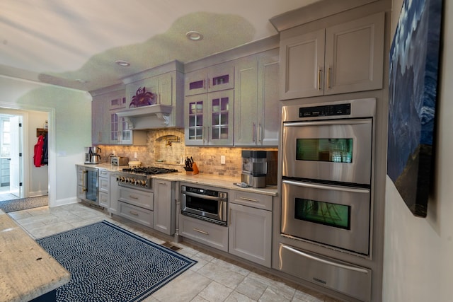 kitchen with beverage cooler, decorative backsplash, glass insert cabinets, appliances with stainless steel finishes, and a warming drawer