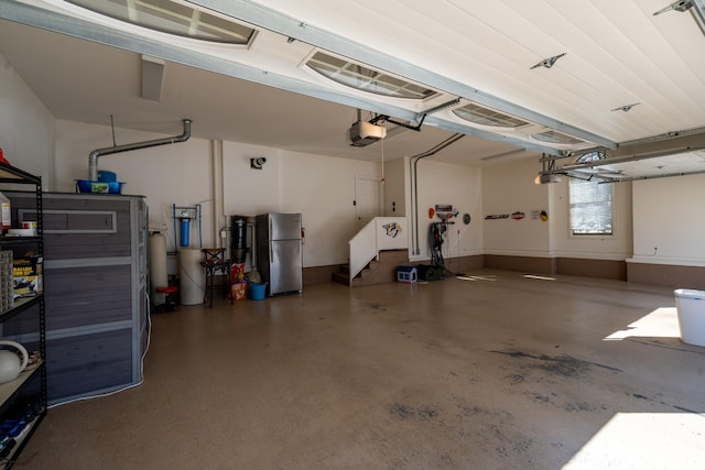 garage with a garage door opener and freestanding refrigerator