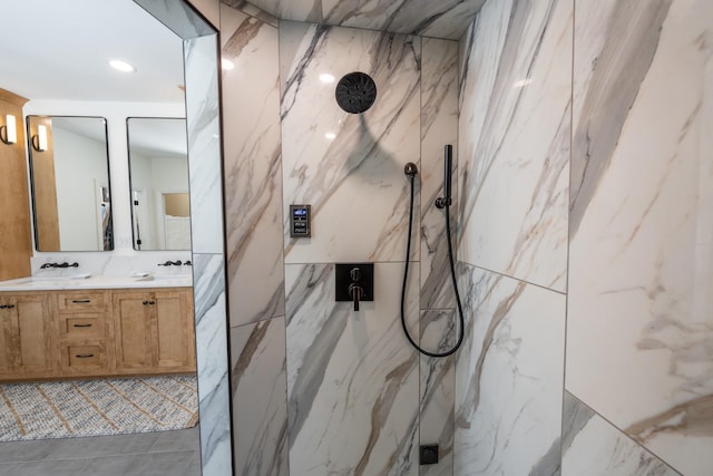 bathroom with double vanity, a marble finish shower, and a sink