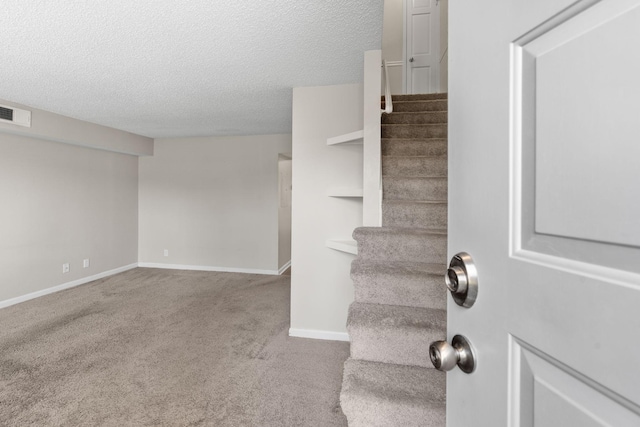 stairs featuring carpet flooring, visible vents, a textured ceiling, and baseboards