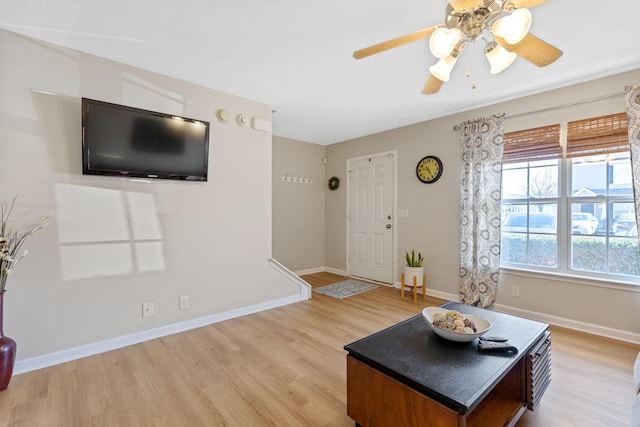 living area with light wood-style floors, baseboards, and ceiling fan