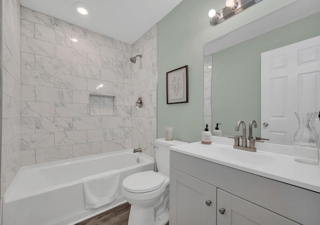 bathroom with wood finished floors, toilet, shower / washtub combination, and vanity