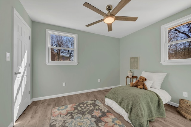 bedroom with a ceiling fan, wood finished floors, and baseboards