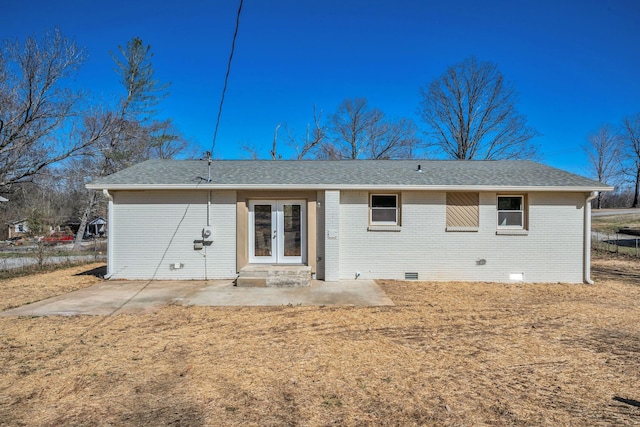 back of property with crawl space, french doors, a shingled roof, and brick siding