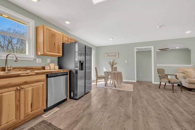 kitchen with light wood-style flooring, a sink, open floor plan, stainless steel appliances, and butcher block counters