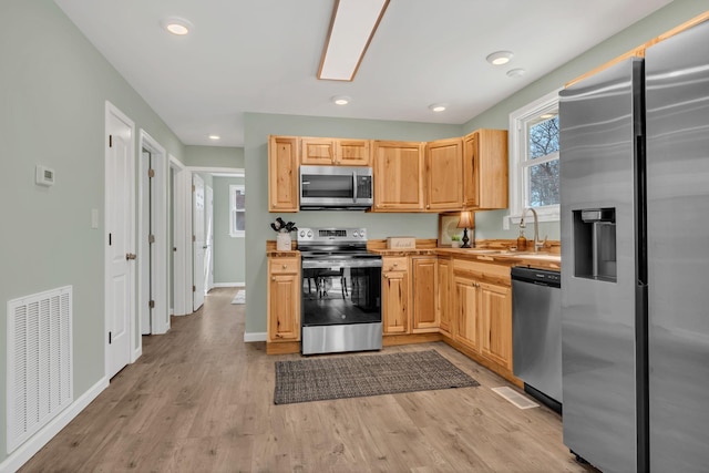 kitchen featuring visible vents, recessed lighting, light wood-style flooring, appliances with stainless steel finishes, and a sink